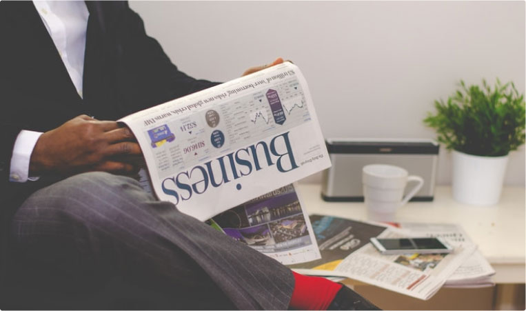 A person reading a business newspaper on top of a table.