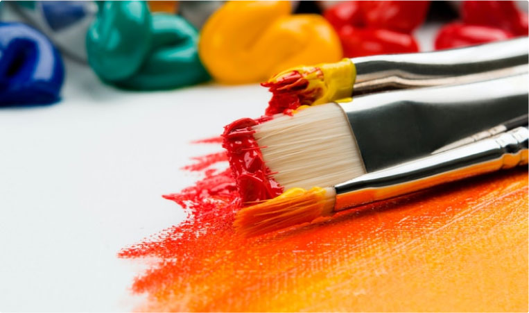 A close up of two brushes with red paint