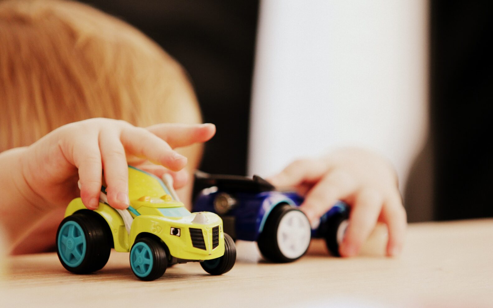 A child playing with toy cars on the table.