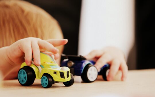 A child playing with toy cars on the table.